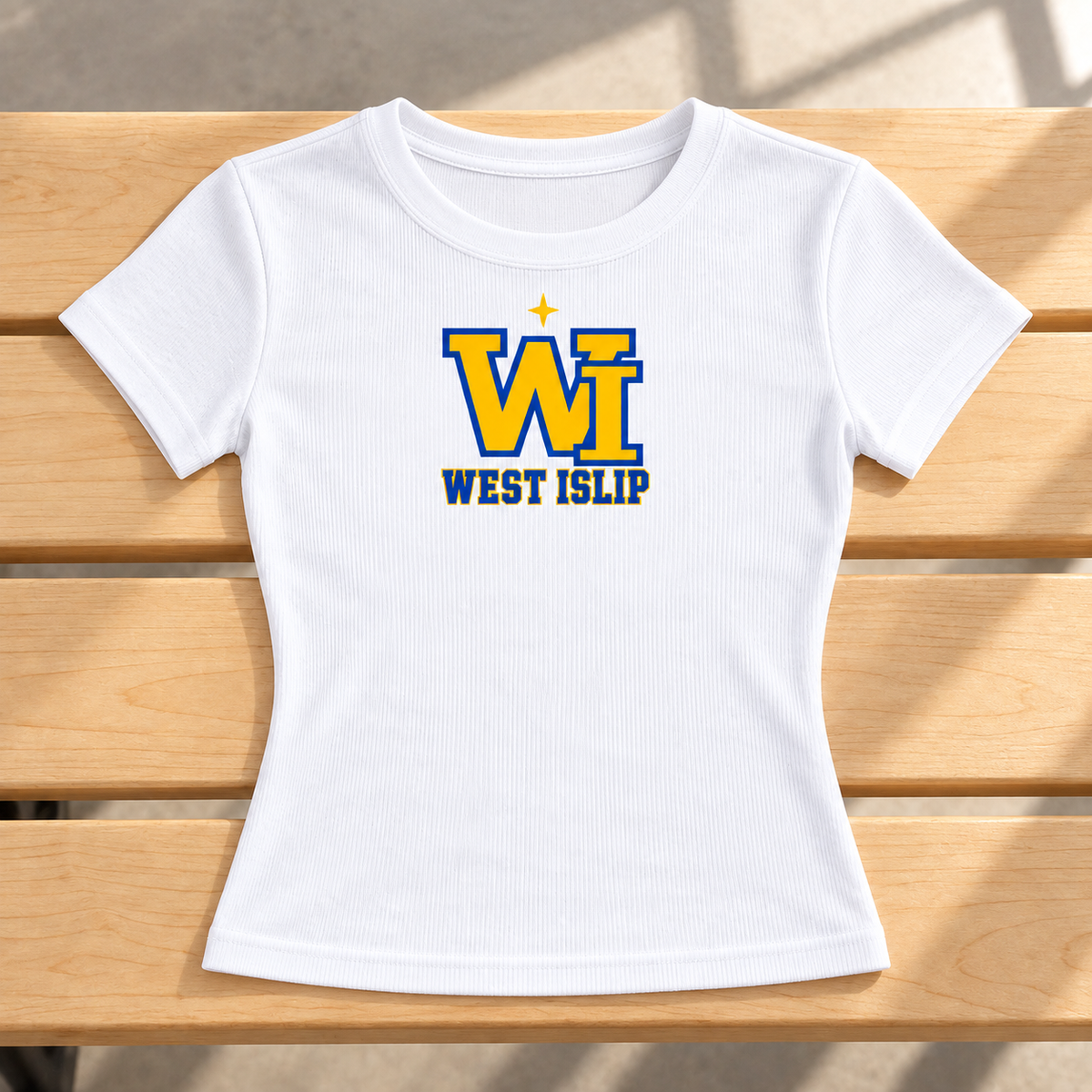 White West Islip women's baby tee laid on a gym bench